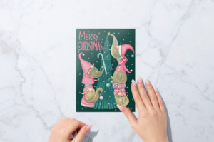 A person's hand holding a "merry christmas" card with whimsical holiday gnomes, displayed against a surrealist marble background.