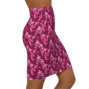 A close-up view of a woman wearing a high-waisted, floral skirt in shades of pink and purple, showcasing the skirt's whimsical design and vibrant pattern.