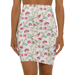 A close-up of a woman wearing a surrealism-inspired floral print skirt featuring pink birds and green foliage. Only the skirt and her hands are visible.