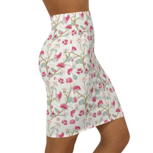 A close-up of a woman wearing a high-waisted floral skirt with a surreal pattern in shades of pink and green on a cream background. The focus is on the skirt from waist to mid-th