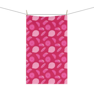 A vibrant pink towel featuring a whimsical pattern of white citrus fruit slices, hanging from a clothesline against a white background.