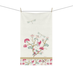 A decorative hanging towel featuring a whimsical floral and dragonfly design in pastel colors, strung on a line against a white background.