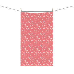 A whimsical pink towel with a white butterfly pattern hanging on a clothesline, secured by two wooden clothespins.