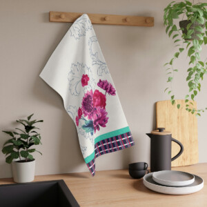A floral kitchen towel hangs on a wooden rack above a modern kitchen counter with a coffee pot, cup, plates, and decorative green plants inspired by the surrealism of Melanie Stimmell's Park West