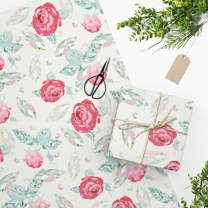 A neatly wrapped gift in Blooms & Gems Custom Wrapping Paper, created by Las Vegas Artist Melanie Stimmell, accompanied by scissors, a sprig of greenery, and a blank tag on a white background.