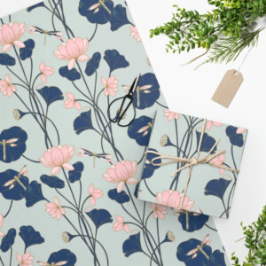 Lotus wrapping paper with a floral pattern in shades of pink and blue, alongside a wrapped gift tied with twine. A sprig of greenery and a blank tag add a natural touch, reminiscent of