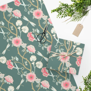 Flat lay of Wrapping Paper Craftsman Rose and notebook, with a black scissor, twine, tag, and green plant sprigs, on a white background.