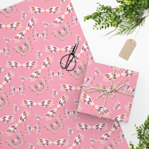 Gift wrapping station with Flying Cuties in Pink Wrapping Paper, scissors, twine-tied box, greenery, and a blank tag featuring a surrealism painting by Melanie Stimmell, arranged on a white