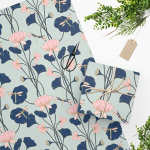 Top view of Lotus Wrapping Paper with pink flowers and blue leaves, accompanied by scissors, a tag, and greenery on a white background.