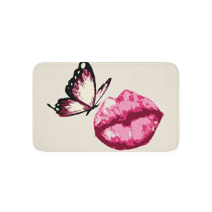 A bath mat featuring a surrealistic graphic design with vibrant pink lipstick-stained lips and a black and pink butterfly perched on the lower lip. The background is light beige.